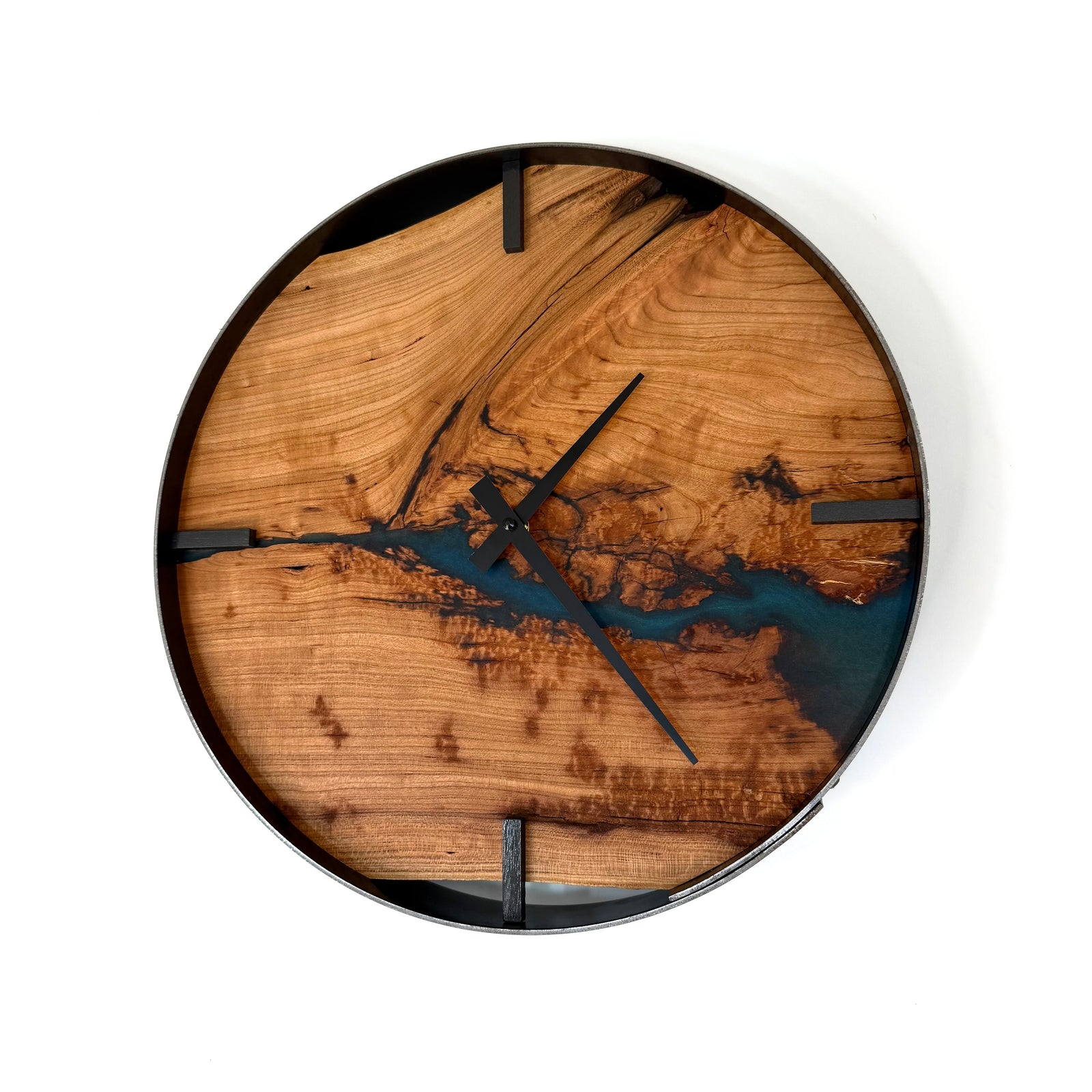 A round wall clock with a natural cherry wood grain face featuring a metallic teal resin river design, black hands, and a black outer rim, shown against a plain white background.
